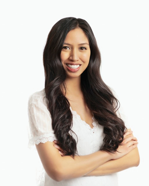 Skin Revolution team member Catherine Carrillo, a registered nurse, posing and smiling in a white shirt