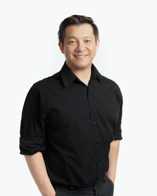 Skin Revolution team member, Dr. Xavier Hsieh standing and posing while smiling in black casual attire
