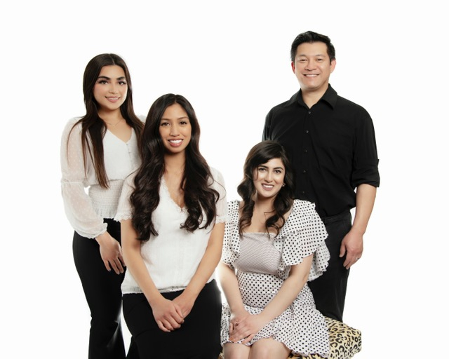 The team at Skin Revolution standing posed together smiling wearing casual dress attire.